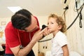 Pediatrician doctor examining child. Male doctor examining boy's ear with otoscope in hospital. Royalty Free Stock Photo