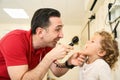 Pediatrician doctor examining child. Male doctor examining boy's ear with otoscope in hospital. Royalty Free Stock Photo