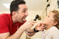 Pediatrician doctor examining child. Male doctor examining boy's ear with otoscope in hospital. Royalty Free Stock Photo