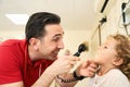 Pediatrician doctor examining child. Male doctor examining boy's ear with otoscope in hospital. Royalty Free Stock Photo