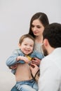 Pediatrician doctor examining happy kid boy. Mother holding baby. Royalty Free Stock Photo