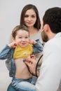 Pediatrician doctor examining kid boy. Mother holding baby. Royalty Free Stock Photo