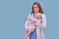 Pediatrician doctor holding newborn baby and smiling, blue studio background. Happy nurse in uniform with a baby in her arms Royalty Free Stock Photo