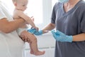 Pediatrician doctor with syringe, tense mother and baby