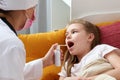 Pediatrician doctor using medical spray for young girl at home, sore throat