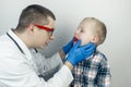 A pediatrician examines a boy who complains of a sore throat. Diagnosis of tracheal diseases. Angina, tonsillitis, pharyngitis,