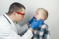 A pediatrician examines a boy who complains of a sore throat. Diagnosis of tracheal diseases. Angina, tonsillitis, pharyngitis,