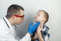 A pediatrician examines a boy who complains of a sore throat. Diagnosis of tracheal diseases. Angina, tonsillitis, pharyngitis,