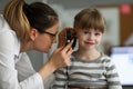 Pediatrician examines ear of sick child in office