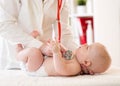 Pediatrician examines five months baby boy. Doctor using stethoscope to listen to child chest checking heart beat Royalty Free Stock Photo