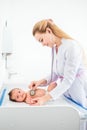 Pediatrician examines two month baby girl. Doctor using a stethoscope to listen to baby`s chest checking heart beat. Child is Royalty Free Stock Photo