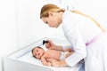 Pediatrician examines 2 week old baby`s ear in new pediatric clinic. Young doctor using otoscope auriscope to check ear canal Royalty Free Stock Photo