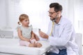 Pediatrician examining baby with stethoscope in clinic