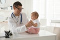 Pediatrician examining cute little baby in clinic. Space for text Royalty Free Stock Photo