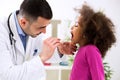 Pediatrician examining cute smiling african girl, throat sick Royalty Free Stock Photo