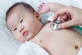 Pediatrician examining infant. Two months baby asian girl lying Royalty Free Stock Photo