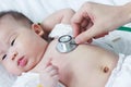 Pediatrician examining infant. Two months baby asian girl lying Royalty Free Stock Photo