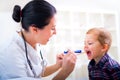 Pediatrician examining little boy's throat with tongue depressor Royalty Free Stock Photo