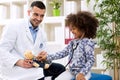 Pediatrician and little african girl treat teddy bear Royalty Free Stock Photo