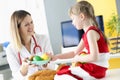 Pediatrician shows little girl different fruits on plate