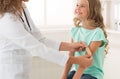 Pediatrician sticking court plaster on girl`s arm