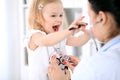 Pediatrician is taking care of baby in hospital. Little girl is being examine by doctor with stethoscope. Health care Royalty Free Stock Photo