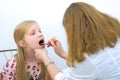 Pediatrician woman looking child girl sore throat using spatula and lantern.