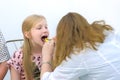 Pediatrician woman looking child girl sore throat using spatula and lantern.