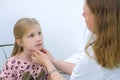 Pediatrician woman probing lymph nodes on neck of girl child during examination.