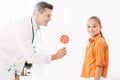 Pediatrist in white coat giving candy to child