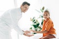 Pediatrist in white coat giving glass of water to child in clinic