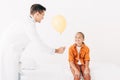 Pediatrist in white coat giving yellow balloon