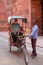 Pedicab driver with a tourist standing outside the wall of Taj M