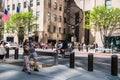 A pedicab is seen riding along an avenue in Manhattan in front of the Atlas statue at Rockefeller Plaza