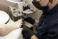 Pedicure in a beauty salon. A masked and gloved craftsman varnishes the clientÃ¢â¬â¢s nails. Close-up