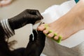 Chiropodist making black gloves making pedicure for her client