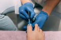 Pedicure process in salon. Foot care treatment and nail. Applying gel polish to nails with a brush. Master in blue gloves makes pe