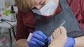 pedicure salon employee uses a nail file during a toe treatment. Close up, selective focus.