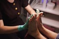 Pedicurist applying nourishing moisturizer cream on woman`s legs and massaging them in pedicure room