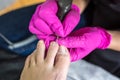 Pedicurist master in pink gloves cuts the cuticle and shellac toe nails in the pedicure salon using drill. Professional pedicure