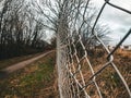 Peeking Through the Barrier: A Wire Fence with a Path and Industrial Landscape Beyond