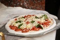 Peel with raw traditional Italian pizza on table in kitchen Royalty Free Stock Photo