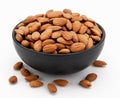 Peeled almonds in a bowl and a few nuts scattered around on a white background