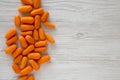 Peeled baby carrots ready to eat on a white wooden background, top view. Overhead, from above, flat lay. Copy space Royalty Free Stock Photo