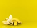 Peeled banana and bunch of bananas on yellow background with copy space Royalty Free Stock Photo