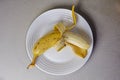 peeled banana on a white plate on a gray table.