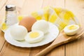 Peeled boiled eggs in white plate, salt and bamboo spoon