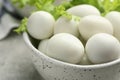 Peeled boiled quail eggs in bowl on grey table