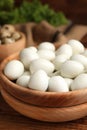 Peeled boiled quail eggs in bowl on wooden table, closeup