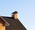 Peeled brick chimney with small roof on the roof top on the house, close up